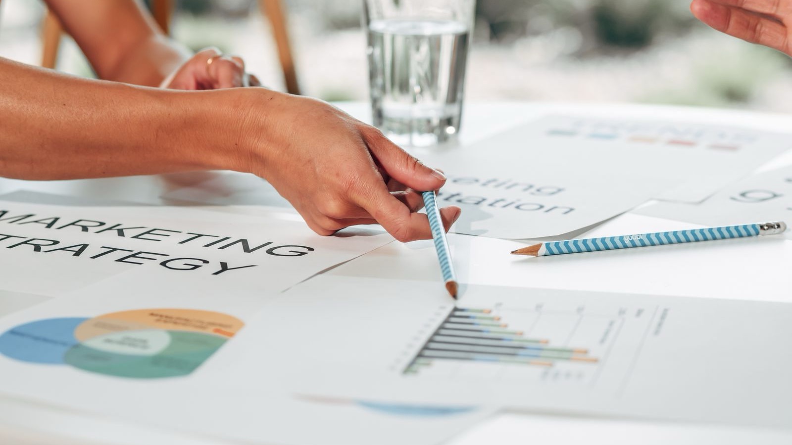 Hands discussing marketing strategy with charts in an office setting.
