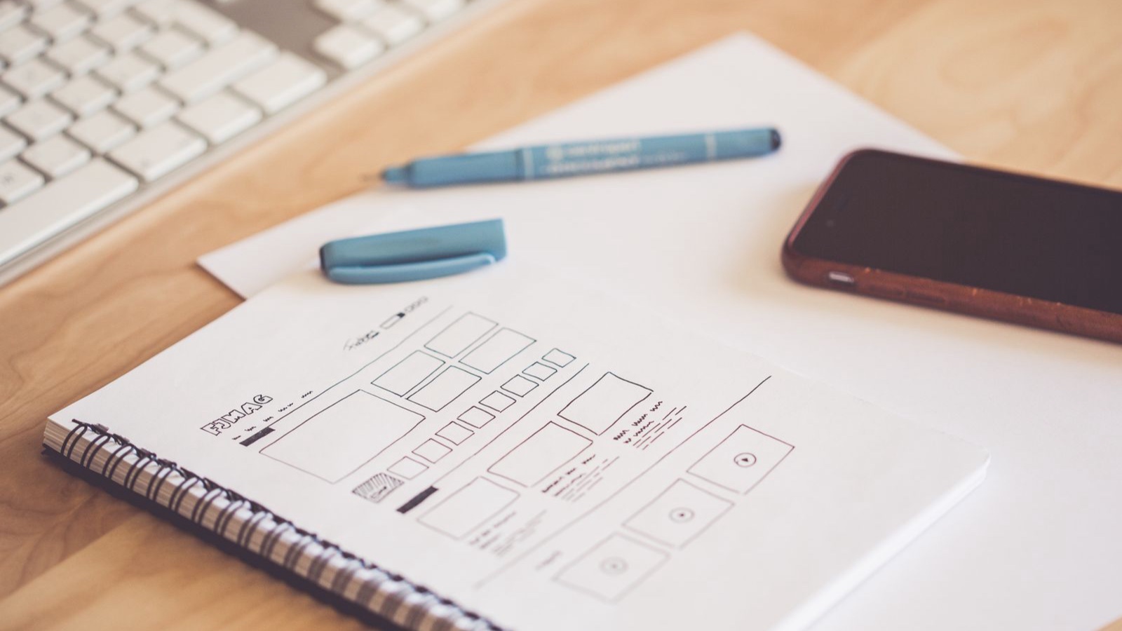 Multipage Websites: Giving Each Service a Useful Explanation Website wireframe sketches on paper beside a smartphone and pen.
