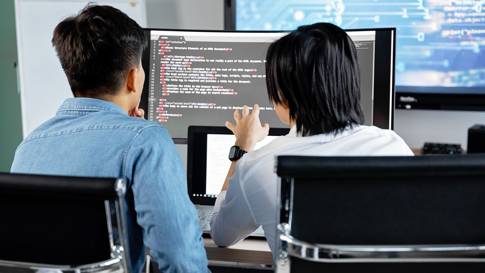 Two people reviewing work on a computer screen