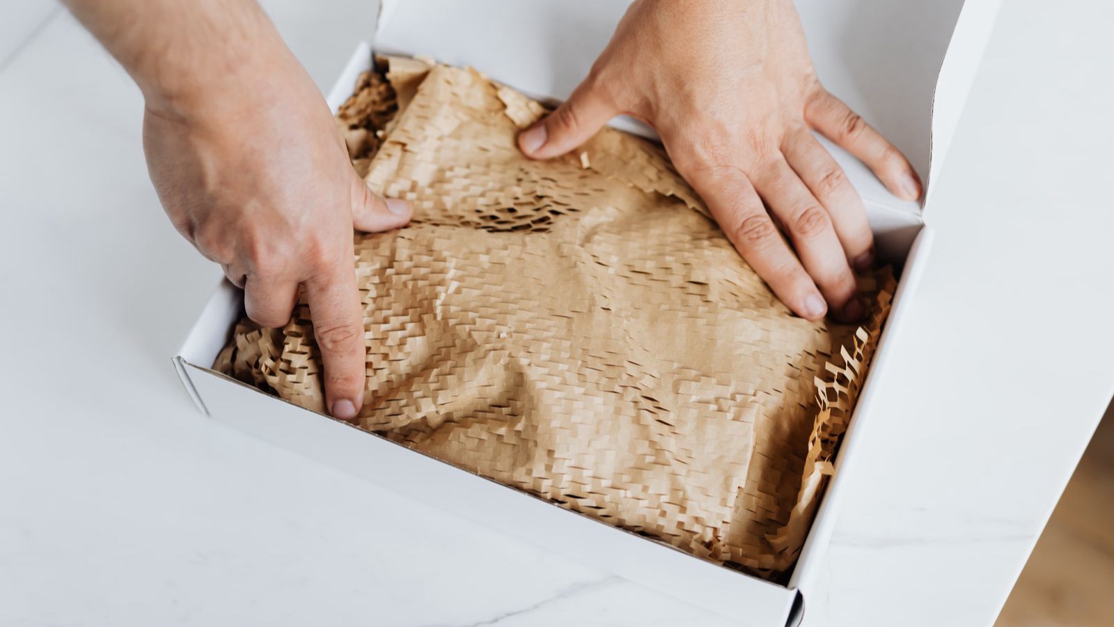 Shipping Integration: From Labels to Reliable Delivery Status Hands placing protective paper inside a shipping box