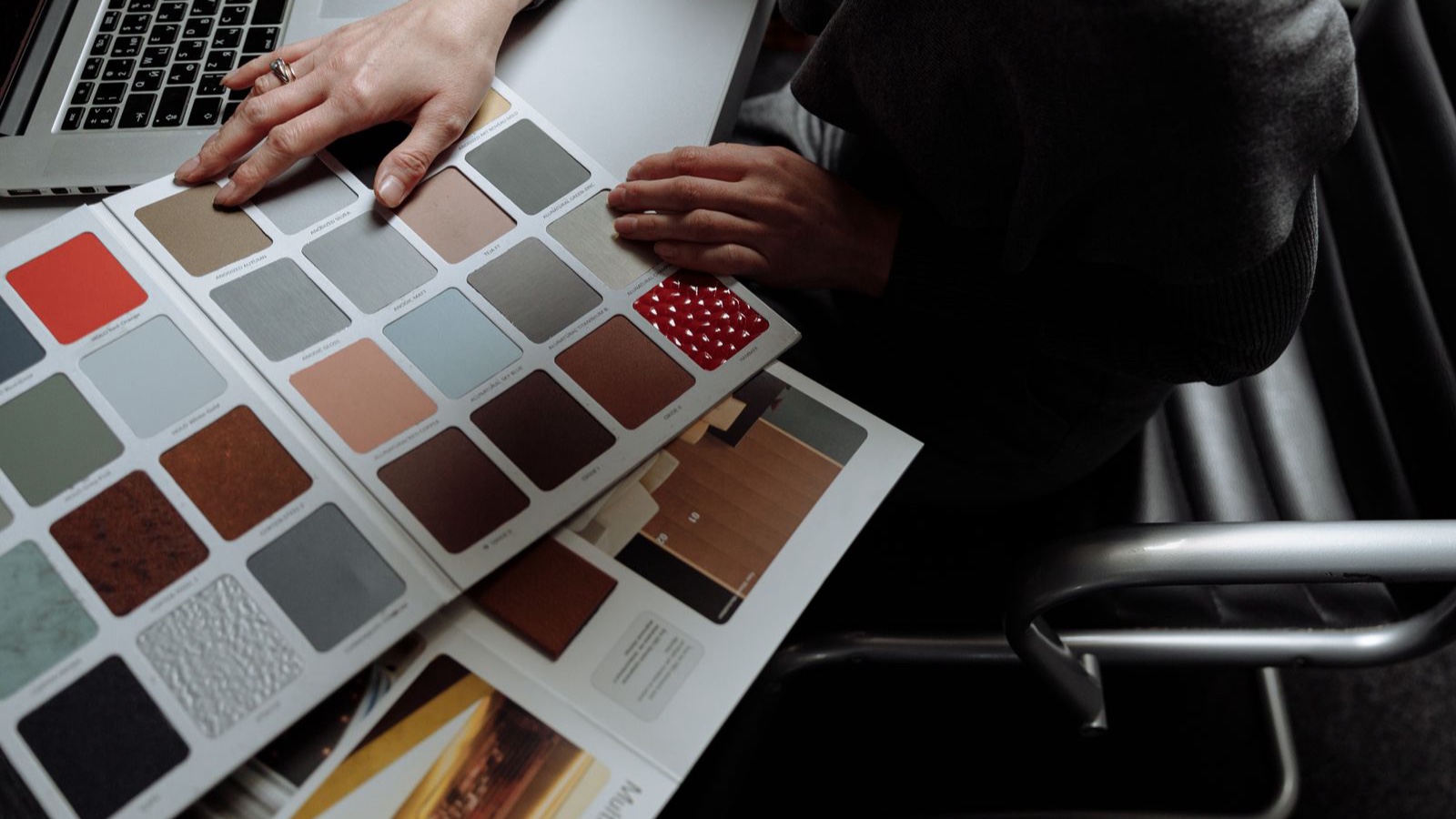 A person reviewing an open colour swatch book at a desk