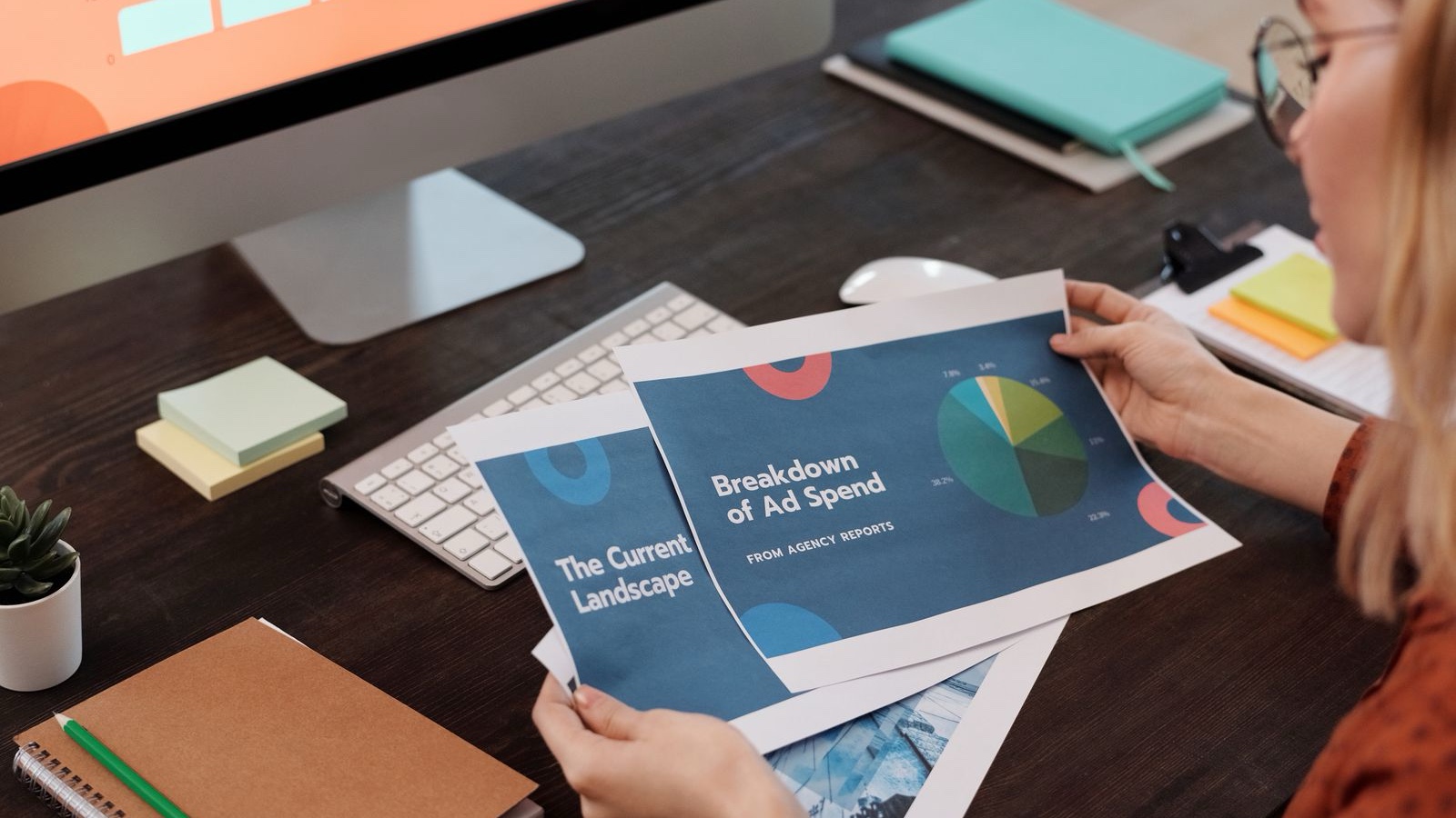 UTM conventions: Why campaign names need a shared standard A person reviewing printed graphic design examples beside a laptop
