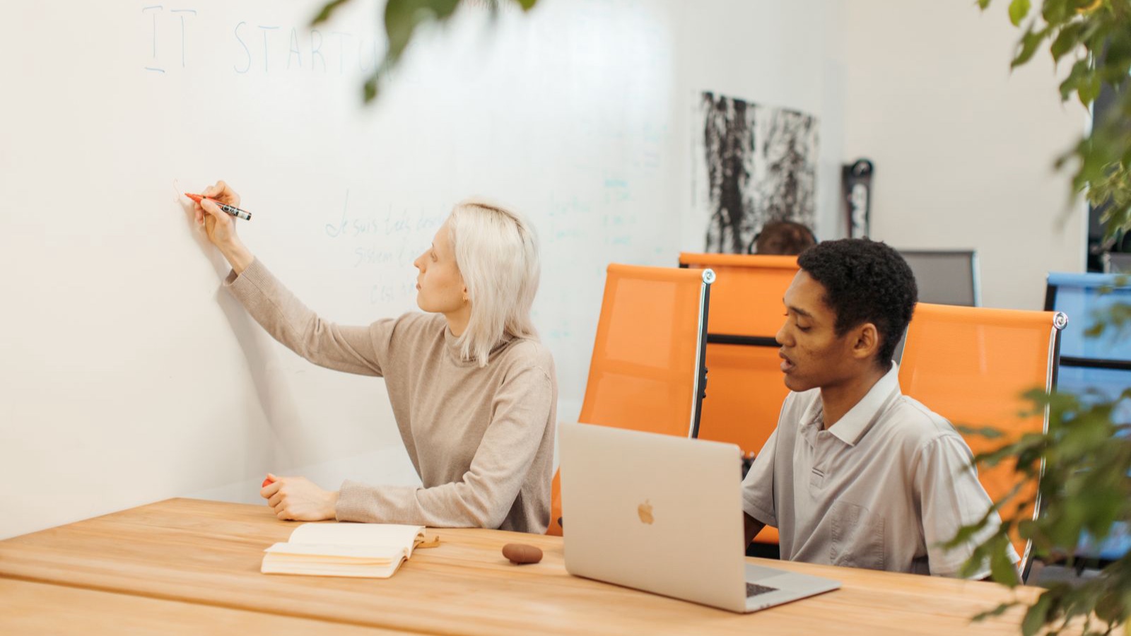 Startup brand identity: What to prioritise for the first launch A woman writing on a whiteboard beside a man working on a laptop