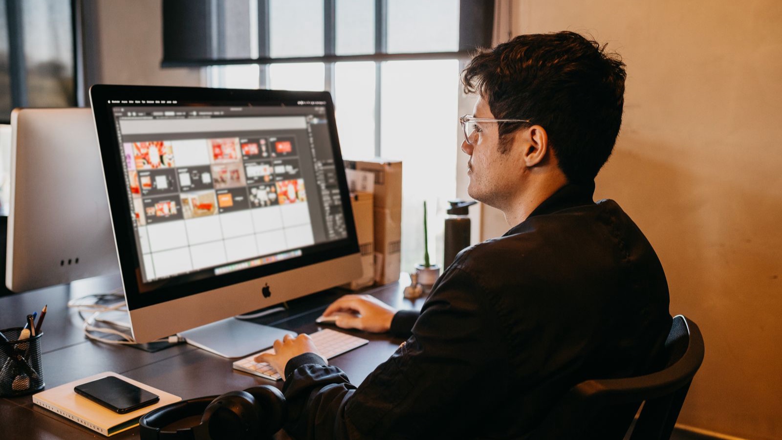 Design file handover: Sources, outputs and version control A designer reviewing visual layouts on a desktop monitor