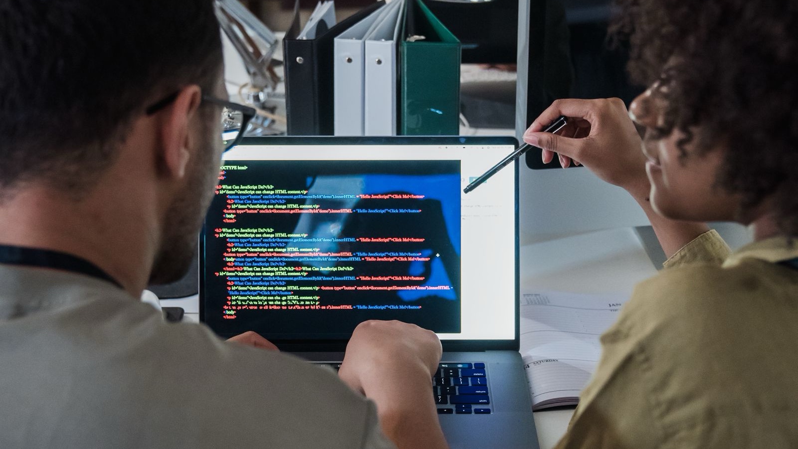 Website Launch Review: Walk Through Real User Tasks Before Release Two developers engage in software programming on a laptop in a modern office setting.