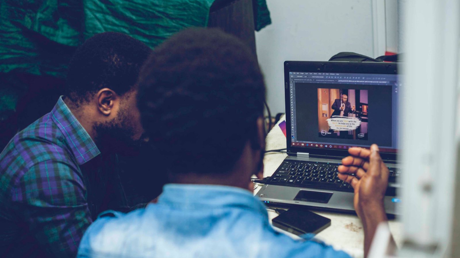 Web Design Pricing: Compare the Scope Behind Each Proposal Two men collaborating on graphic design using a laptop indoors, focusing on technology and teamwork.